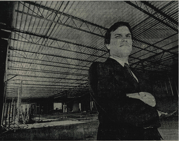 Harold Muckleroy standing, staring sternly at the camera