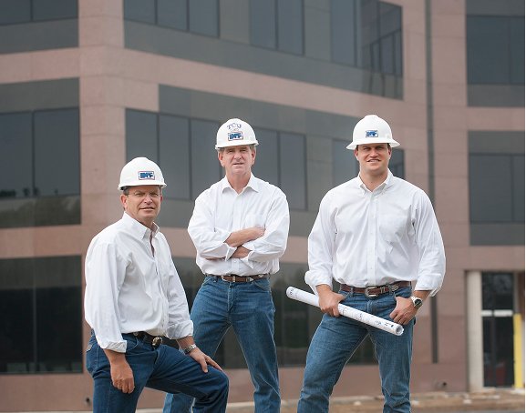 Zach Muckleroy, Harold Muckleroy, and Max Falls standing in front of a building