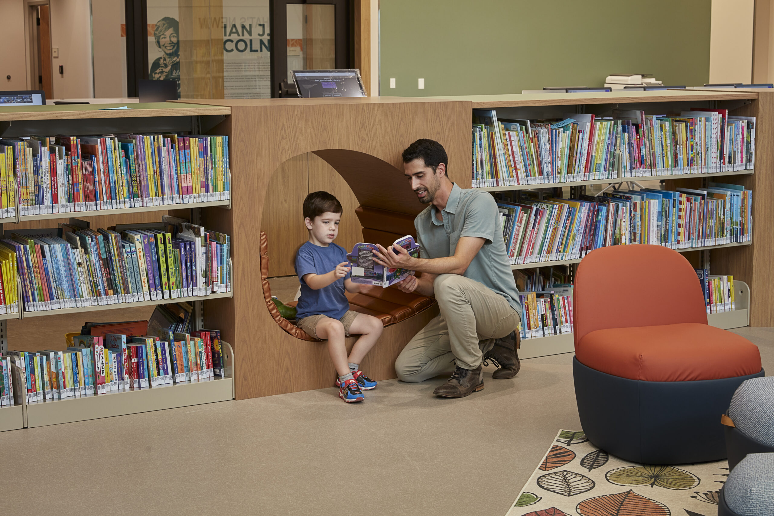 Adult reading to a chid in a library